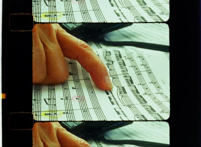 Finger pointing to a music note on a music sheet