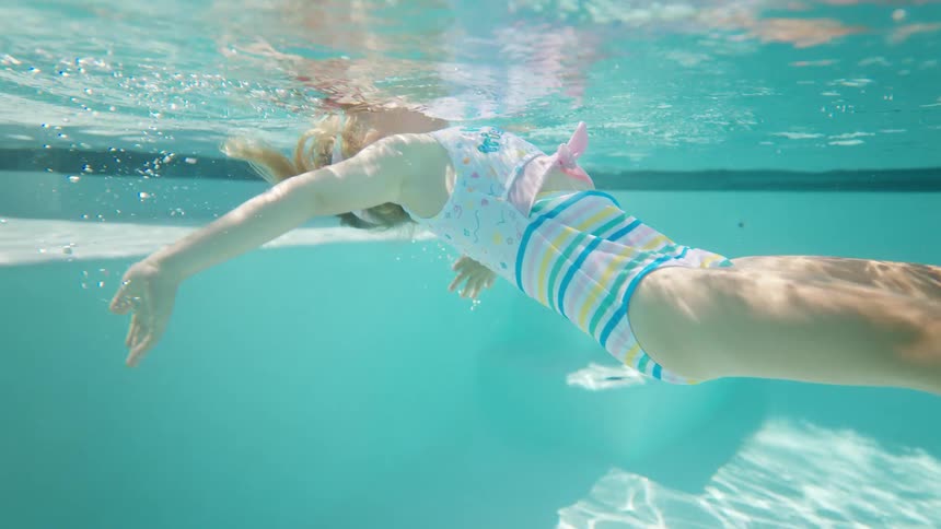 The girl is swimming in the pool on a sunny day