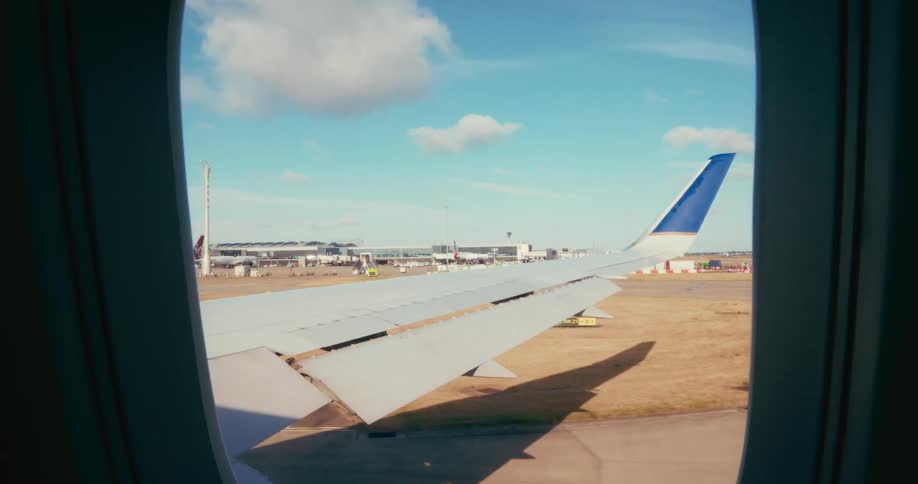 The wing of an aircraft moving on a runway in an airport during daytime