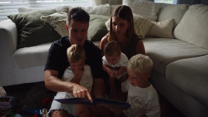 A family sits on the floor looking at a photo album together