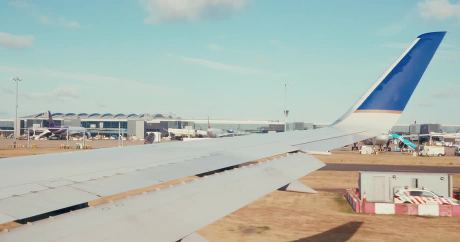 The plane is taking off on the runway by the large airport