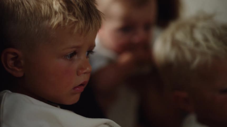 Two young brothers and an infant are all together while indoors