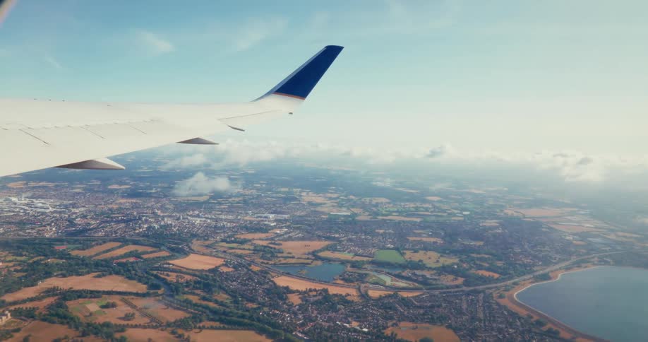 Aerial view from a plane window showing neighborhoods and land below