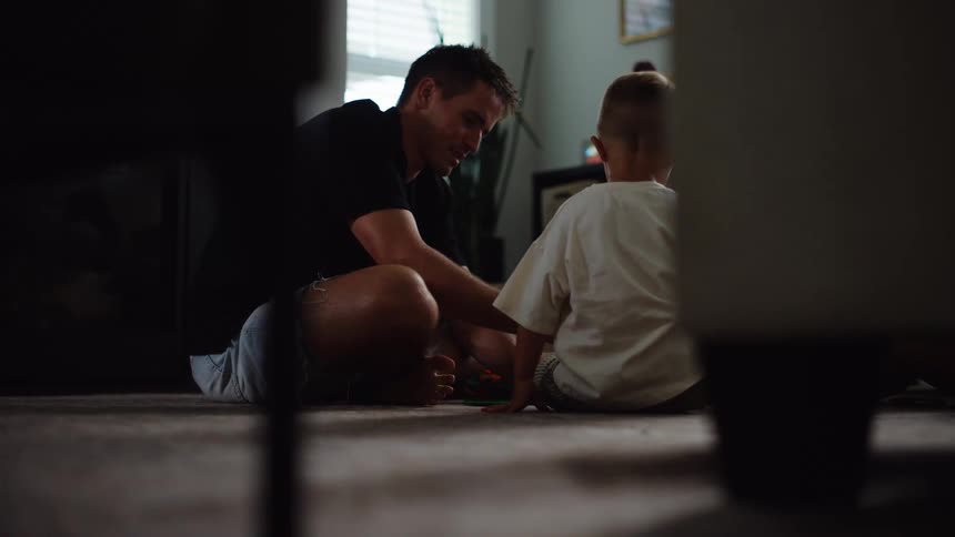 Father and son play together on the living room floor