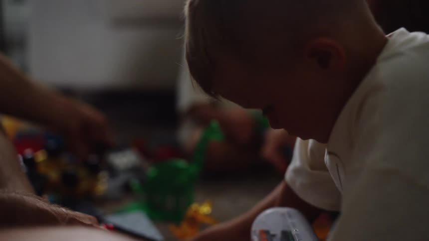 A group of children are playing on the floor of a living room using several toys