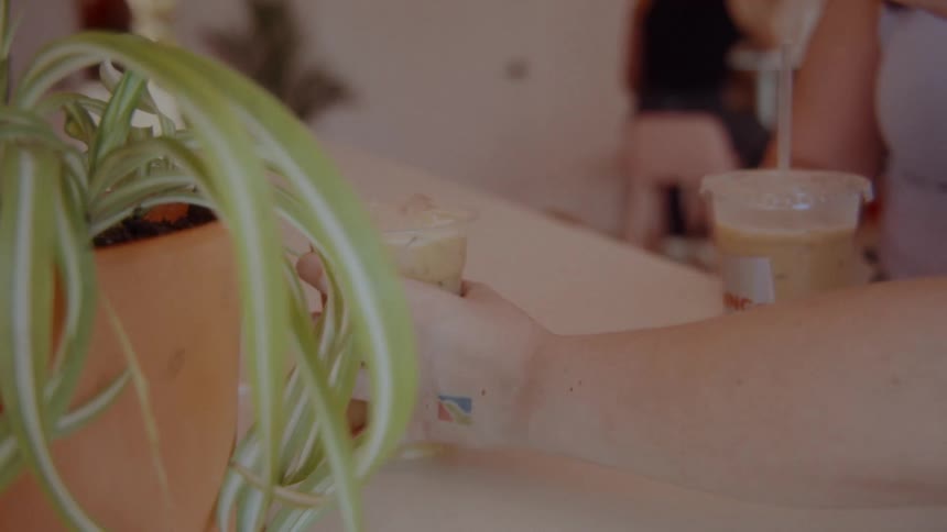 Hands holding iced coffee cups on a counter