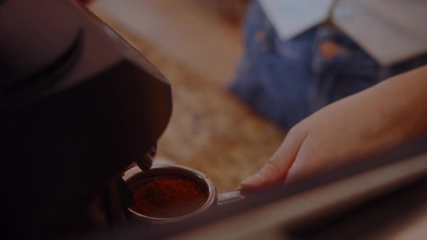 Fresh grounds fill a portafilter on an espresso machine ready to brew