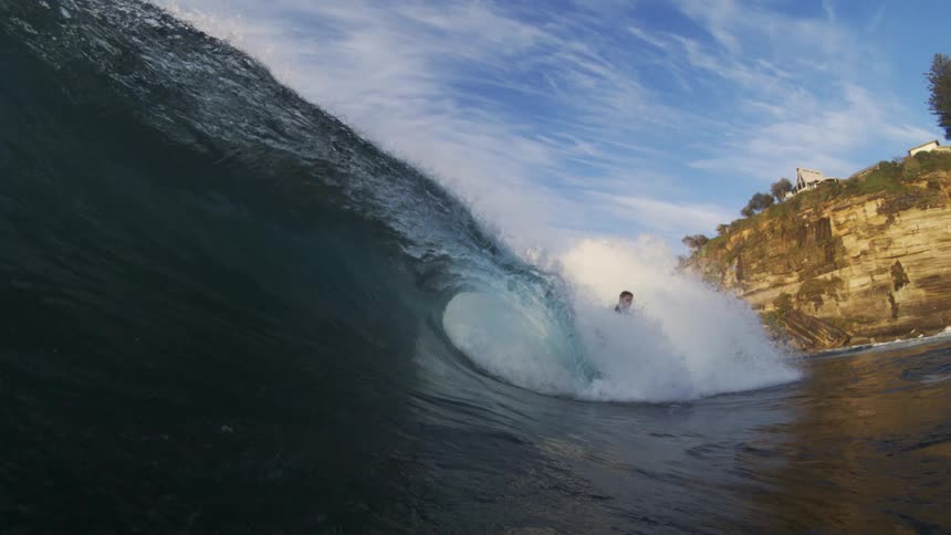 A male surfer rides on an large ocean wave that is curling over