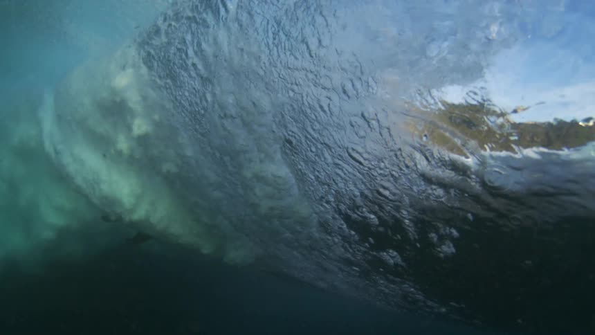 The man crouches while riding a wave on his surfboard