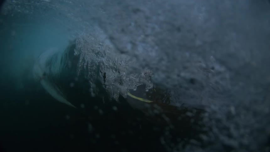A male surfer rides atop his surfboard on an ocean wave