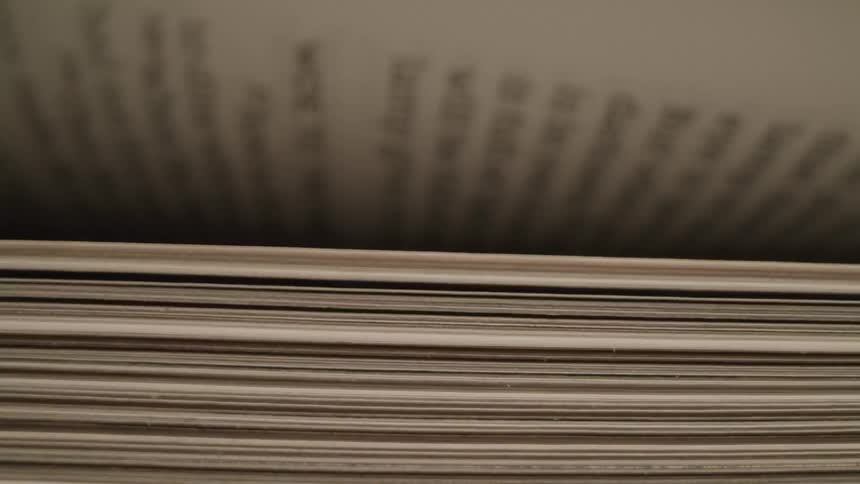 A close up view of book pages being turned it is very close up shot there are some text visible but not quite enough to read it