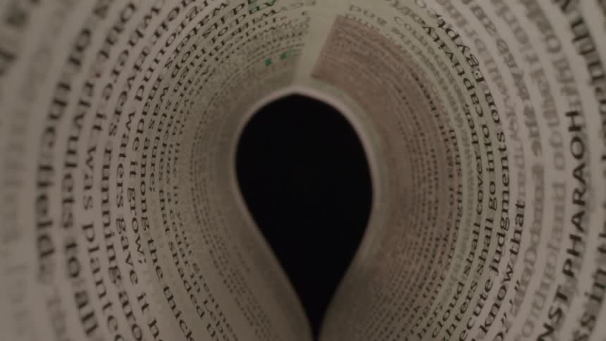A shot taken from inside a rolledup poster or piece of paper shows a black circle in the center and the text on the paper is blurred and out of focus the person holding the paper then unrolls it