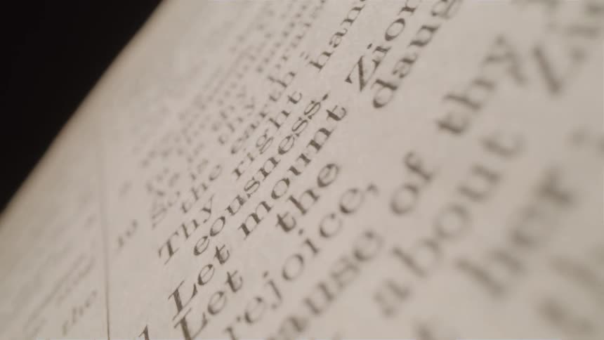 A closeup of a page from the bible is filled with text