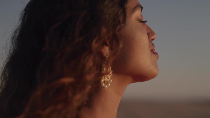 A indian woman with her eyes closed with long hair wearing long earrings