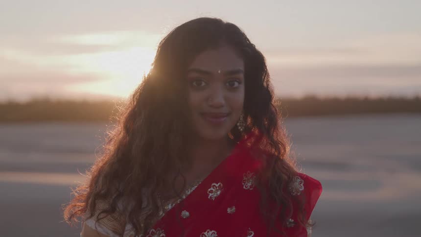 The woman smiles as the sun rises behind her