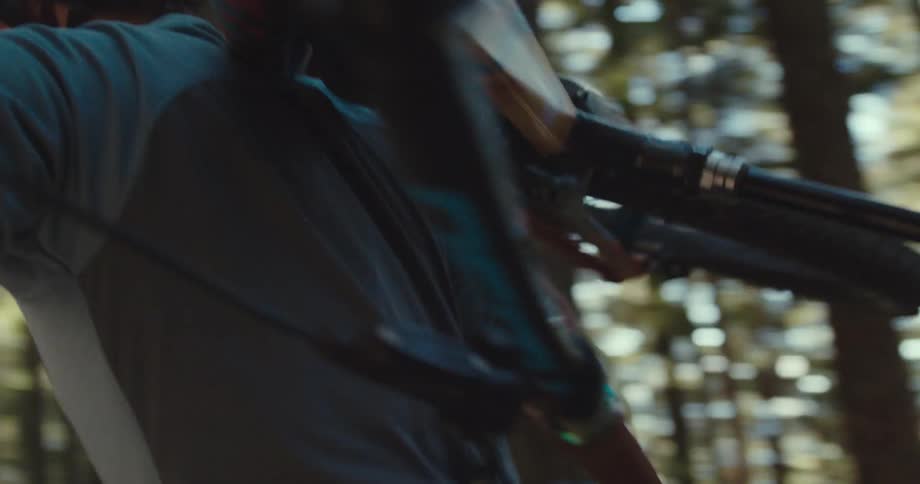 The video shows a person wearing a helmet and gloves riding a bike in a forest the trees are tall and the sun is shining through the leaves creating a bright and airy atmosphere