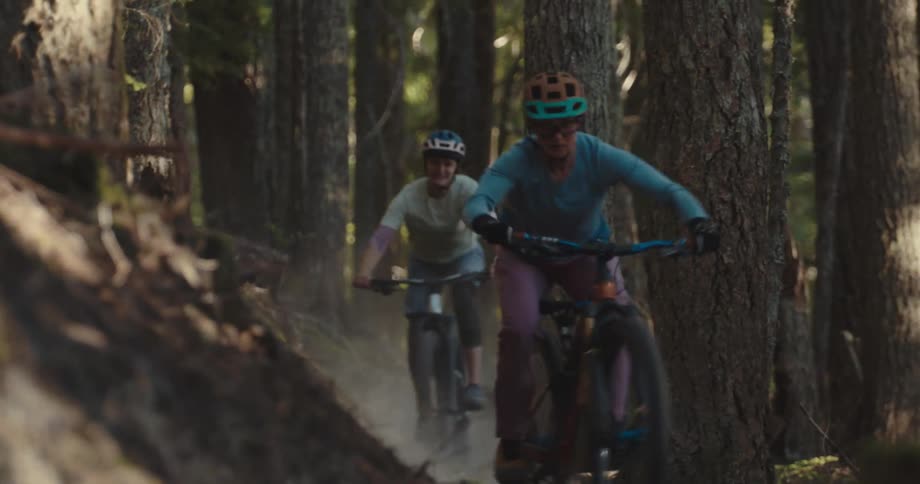 A pair of mountain bikers race along a trail through a forest