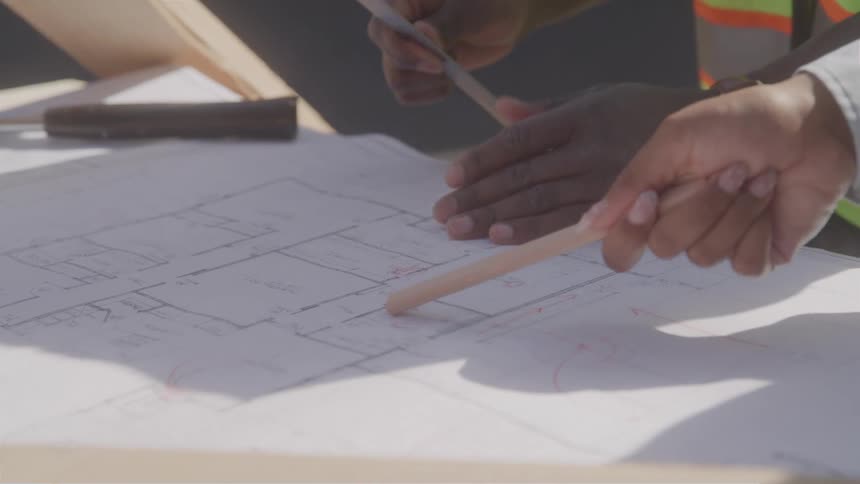 Close up of two construction architects working on a building plan outdoors during daytime