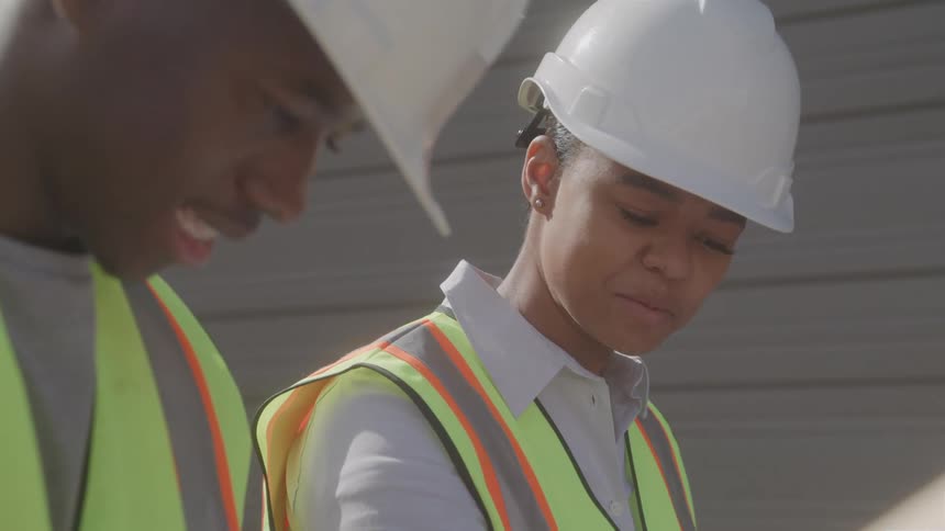 Close up of two construction workers conversing while working outdoors during daytime