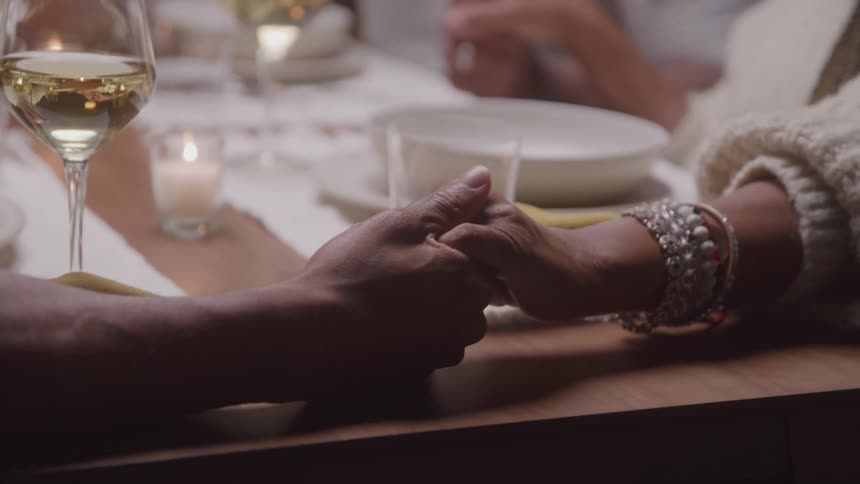 A man and woman hold hands at dinner