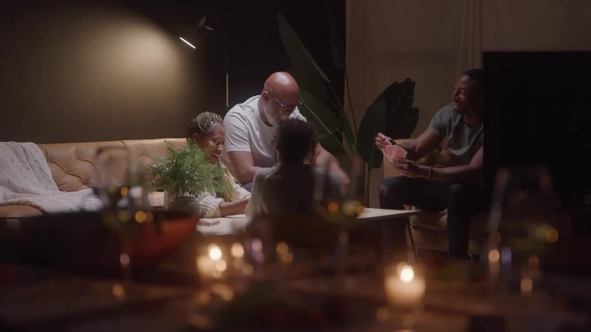 A small group of people in a living room play a card game together