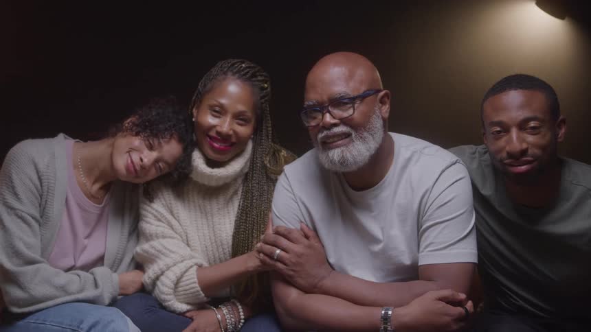 Portrait of a black family of four seating in a lit room