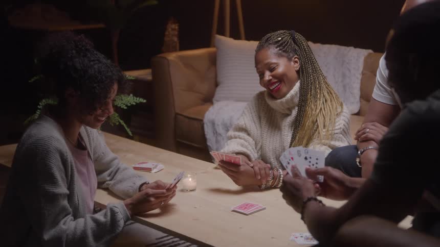Happy family playing card game at table in a modern home