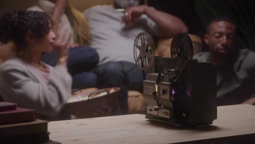 Family watching old movie on retro vintage film projector at home