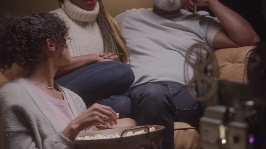 A family watches a movie together with popcorn at home
