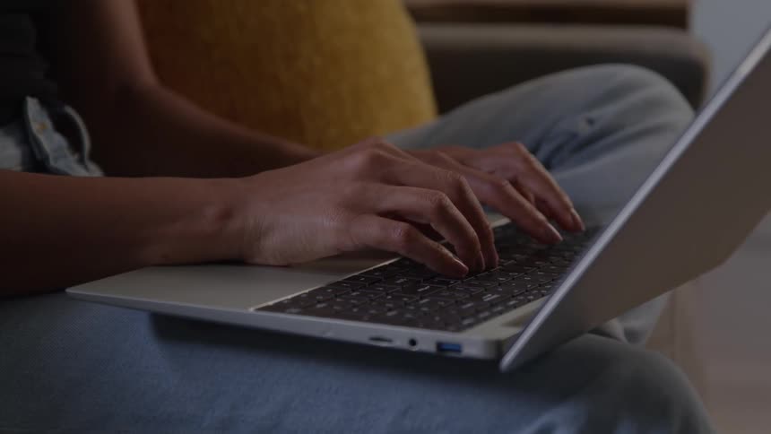 Close up of a young woman typing while using a laptop computer in a room during daytime