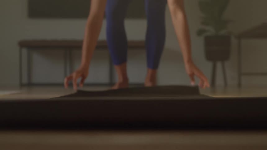 Woman kneeling on a yoga mat prepares for exercise