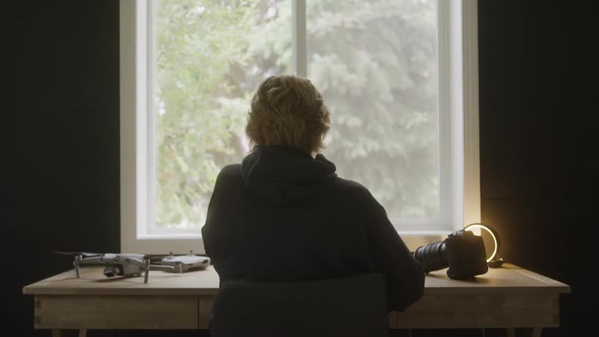 A person works at a desk with tech equipment by a window