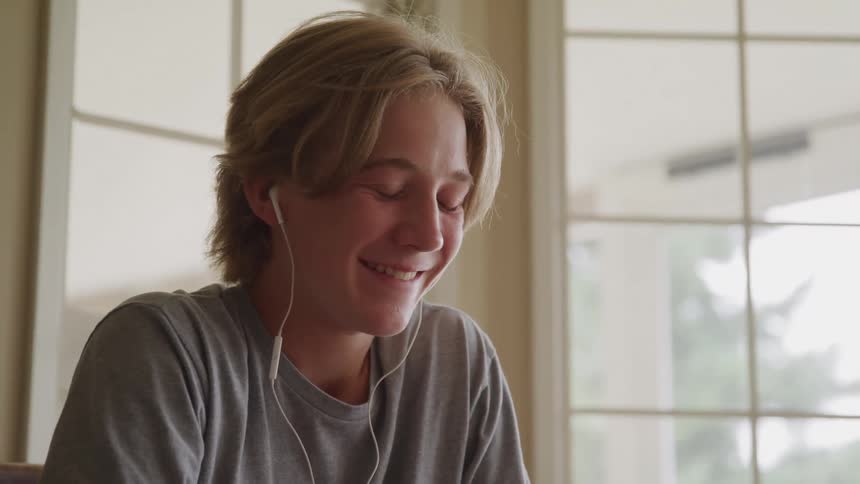 A person with earbuds smiles and laughs