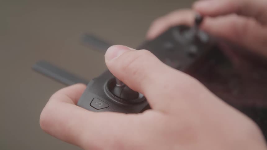 A persons hands manipulate a drone remote controls joysticks and buttons