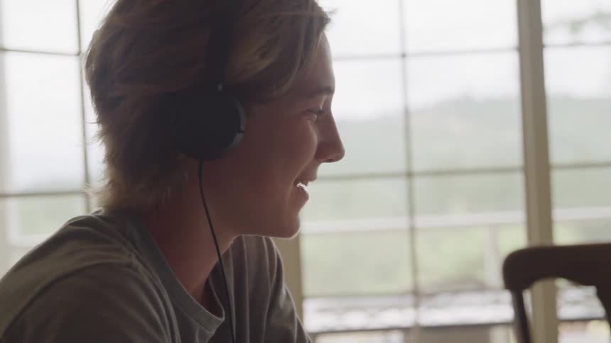 The woman is smiling and talking with headphones on