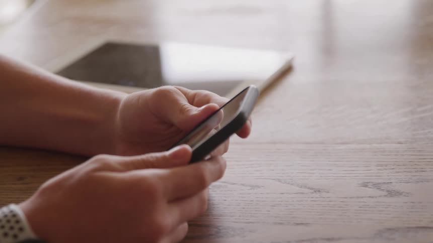 A person holds a phone and scrolls on the screen with their thumbs