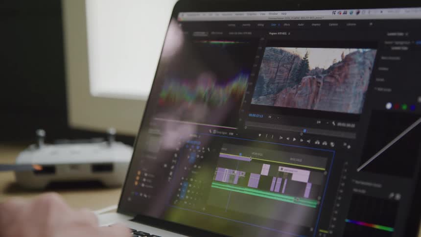 A computer monitor shows a video editing program with tools and a preview of outdoor footage