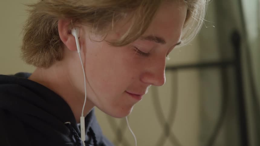 The person has their eyes closed while listening to earbuds