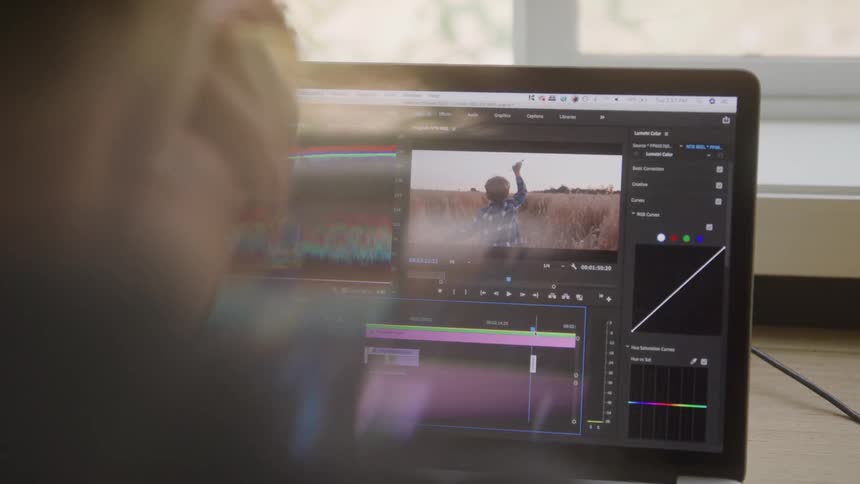 The video shows a person using a laptop with professional video editing software open the screen displays a timeline with multiple clips and an editor suggesting the person is in the process of creating or finalizing a video project