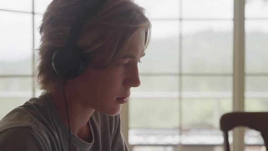 Young person wears headphones while looking ahead in a bright room
