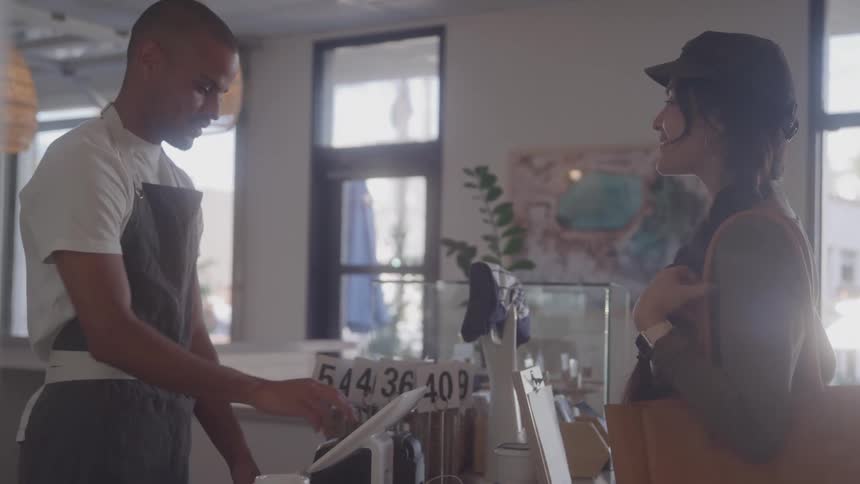 A male worker smiles at a female customer as he inputs her order