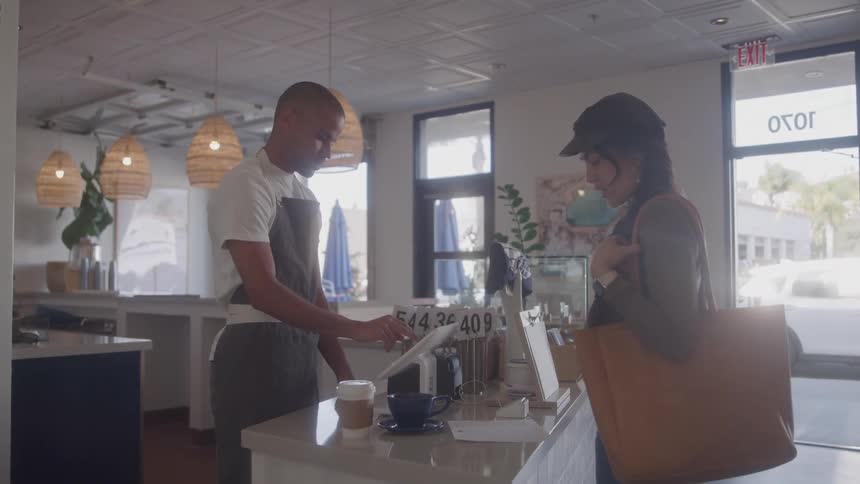 A female customer talks to the male employee at a coffee shop