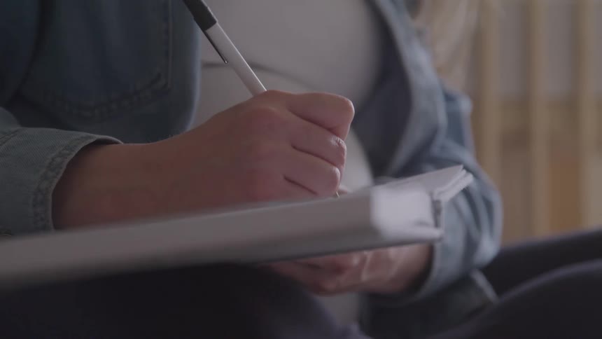 Hand writing in a notebook with a black pen