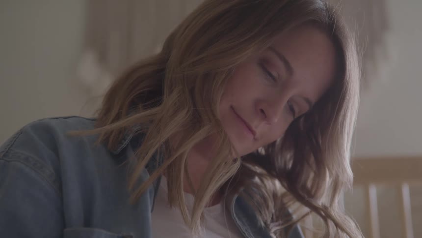 Light brownhaired woman looks downward with a gentle expression
