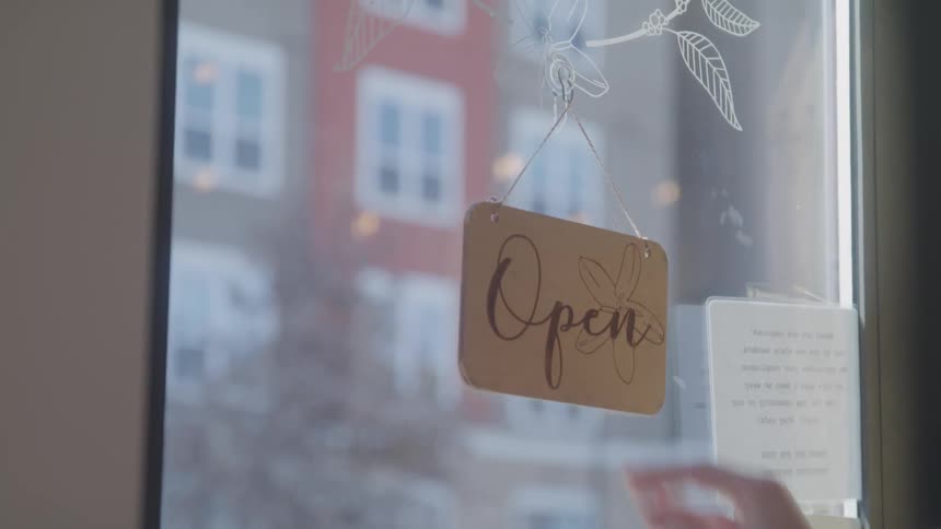 A person turns a sign on the door to closed