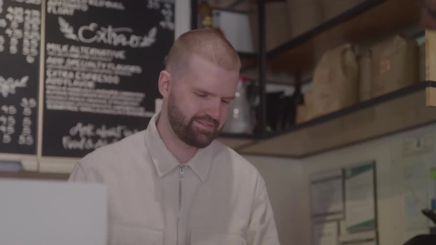 A server stands behind a counter taking an order in a cafe