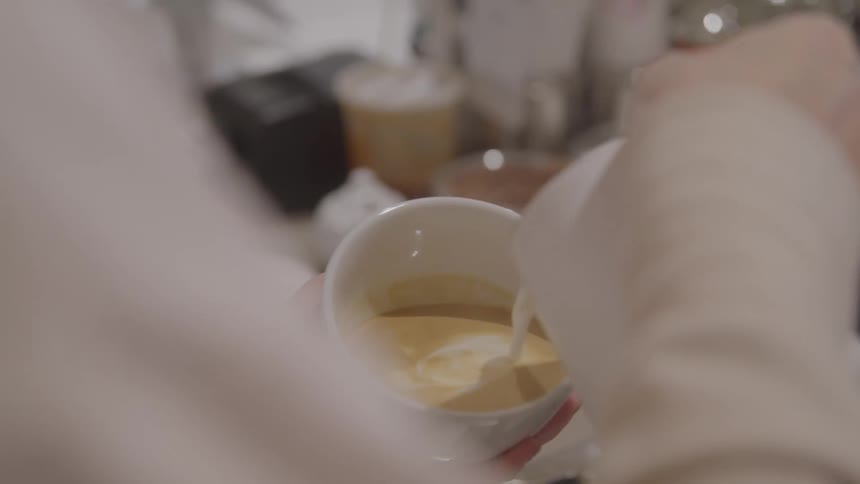 Milk being poured into a cup of espresso