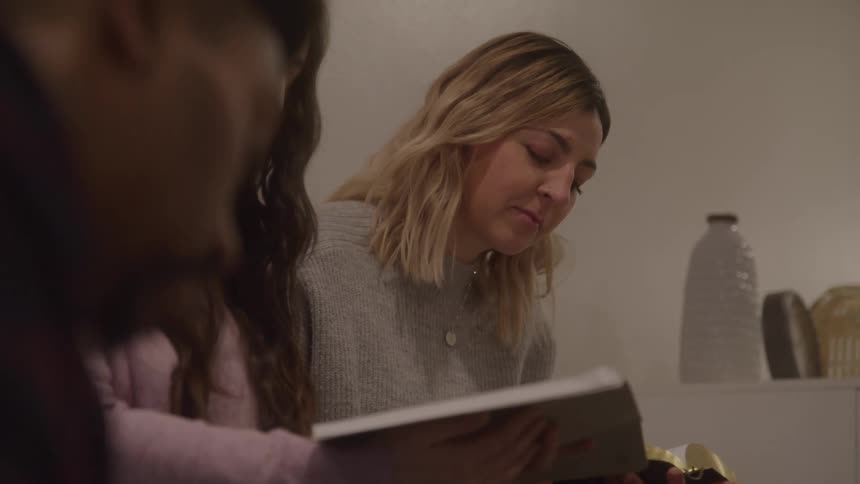 Friends sit close and read from a book together quietly discussing notes