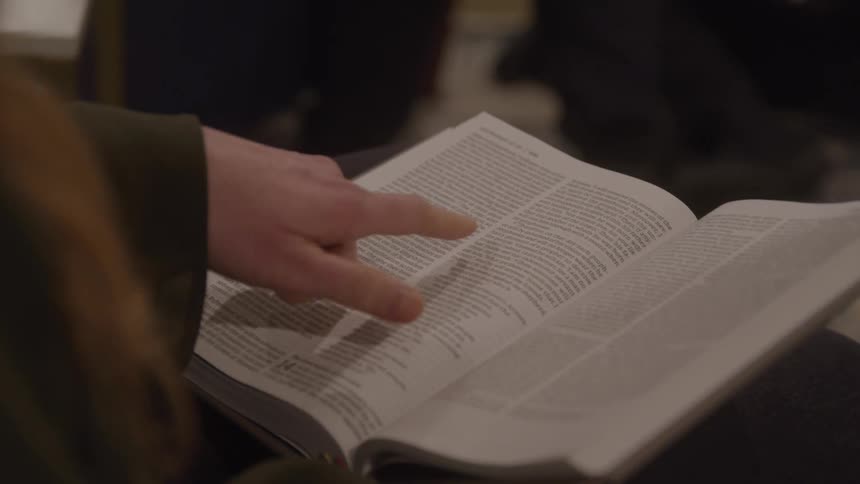 Close up of a young woman reading a bible while sitting in a room