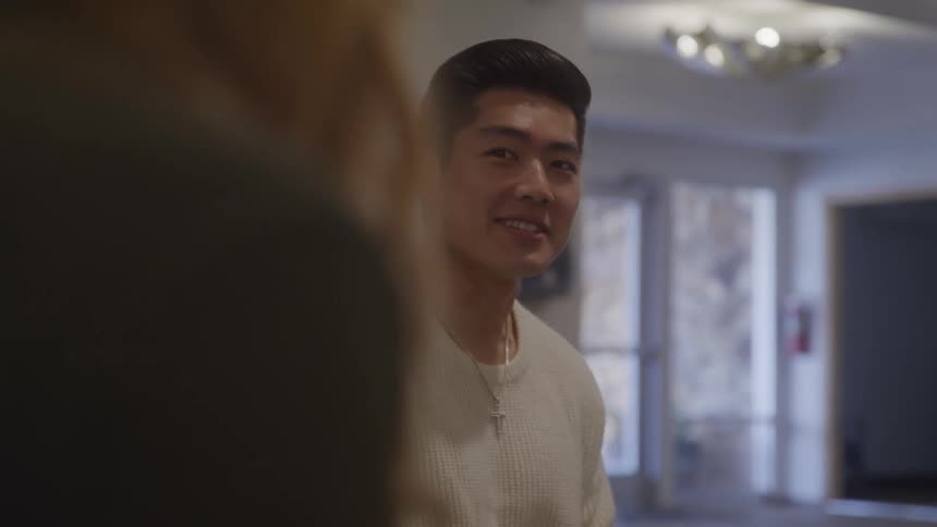 A person in a sweater smiles and turns to the side